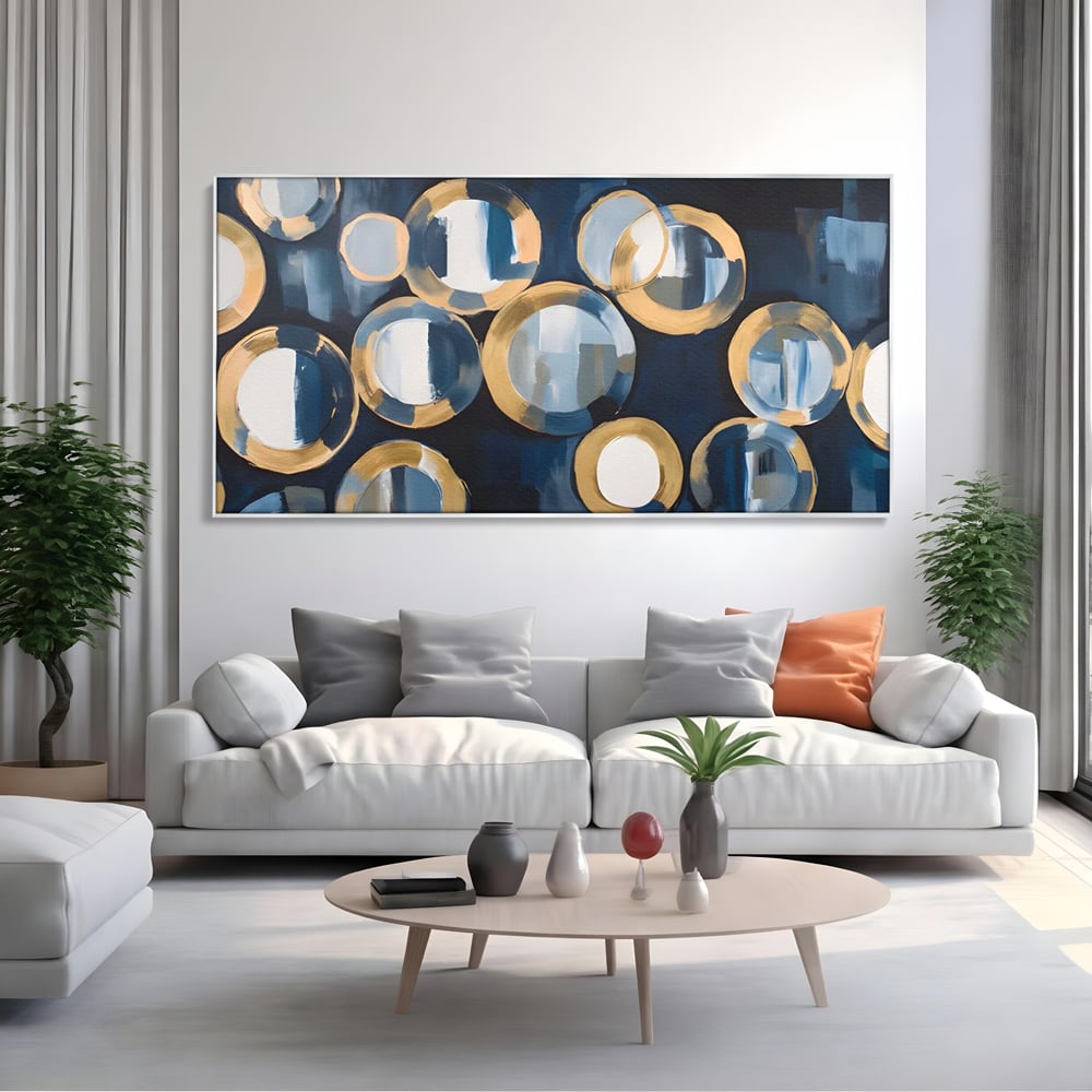 Tablou canvas cu pictura abstracta cu cercuri albastre si aurii, in rama de aluminiu argintiu, pe perete intr-un living